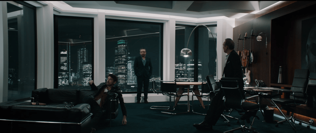 Three men standing and sitting inside a modern office at the top floor of a London skyscraper, from the film Feedback.