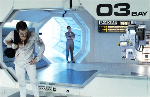 Screencapture from Moon. A man in overalls looks at a bloodied version of himself standing at the opposite side of the room.