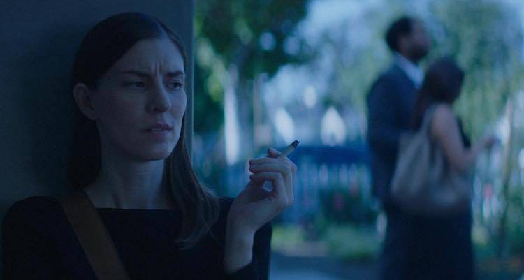 jane smoking while leaning against the house, listening to a couple gossip about her friend