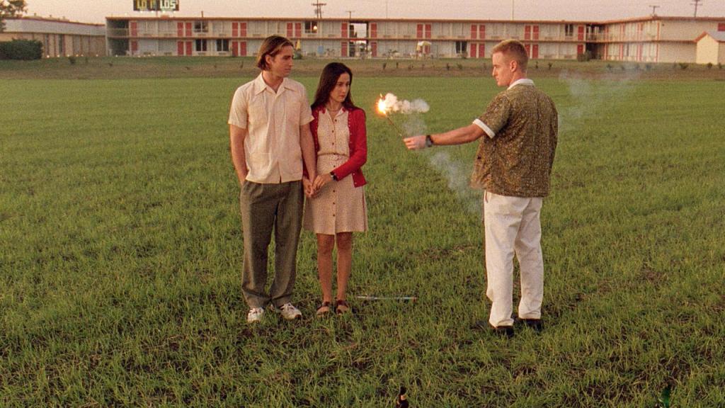Screencapture from Bottle Rocket. A man holds a lit firework whilst another man and woman look on confused. 