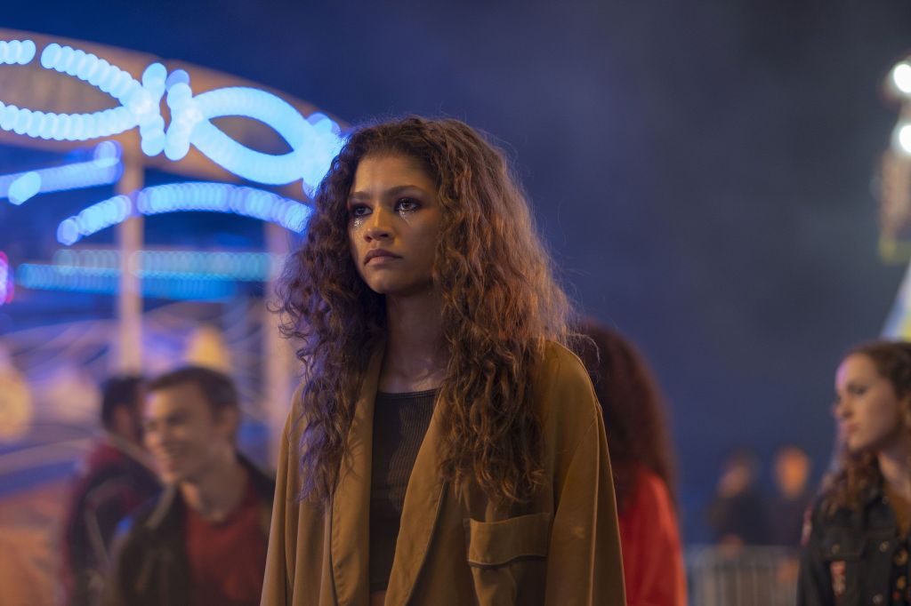 Rue stands amongst the crowd at a fairground. She looks distressed.