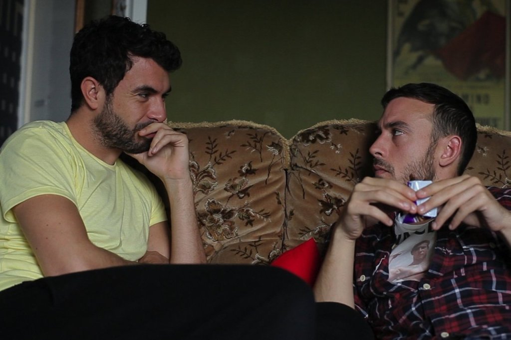 Russell and Glen are engaged in conversation. One is wearing a pale yellow shirt, the other a red plaid shirt.