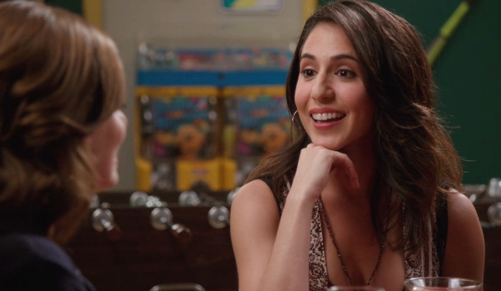 Valencia is engaged in conversation. Her hand is under her chin.