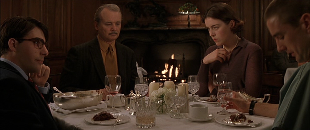 Screencapture from Rushmore. 3 men and a woman sit at a table in a restaurant. 