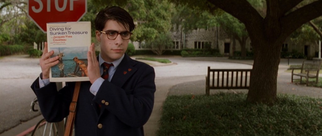 Screencapture from Rushmore. A teenager holds up a book. 