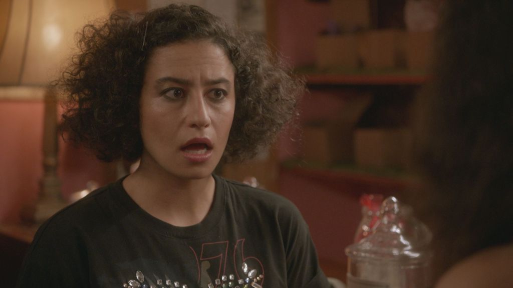 Ilana - a woman with curly hair - stands agape.