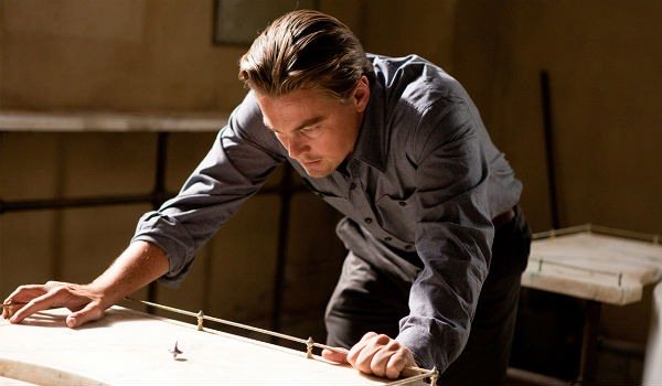 Leonardo DiCaprio in a scene from the film 'Inception.' His character is hunched over, watching a top as it spins.