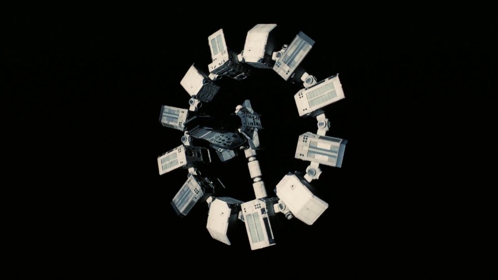 The Endurance space craft, composed of a station at the center surrounded by twelve stations in a circle like the twelve items of a clock. A corridor is connecting the center to one of the twelve stations like the hand of a clock. The Endurance spins, representing time going by.