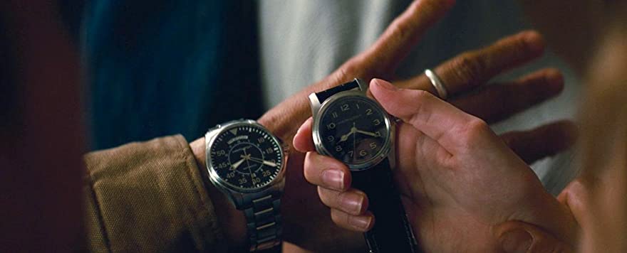 Cooper’s watch is on his wrist, he has just given the other one to Murph, they are comparing them