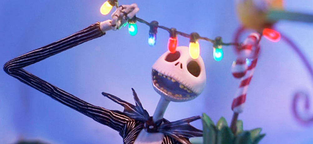 a claymation skeleton wearing a striped suit smiles at colorful string lights