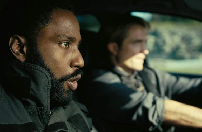 Actors John David Washington and Robert Pattinson in a car, a snapshot from Tenet’s trailer