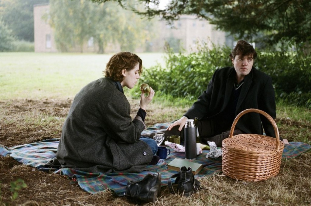 Image from The Souvenir. A couple are having a picnic in a park.