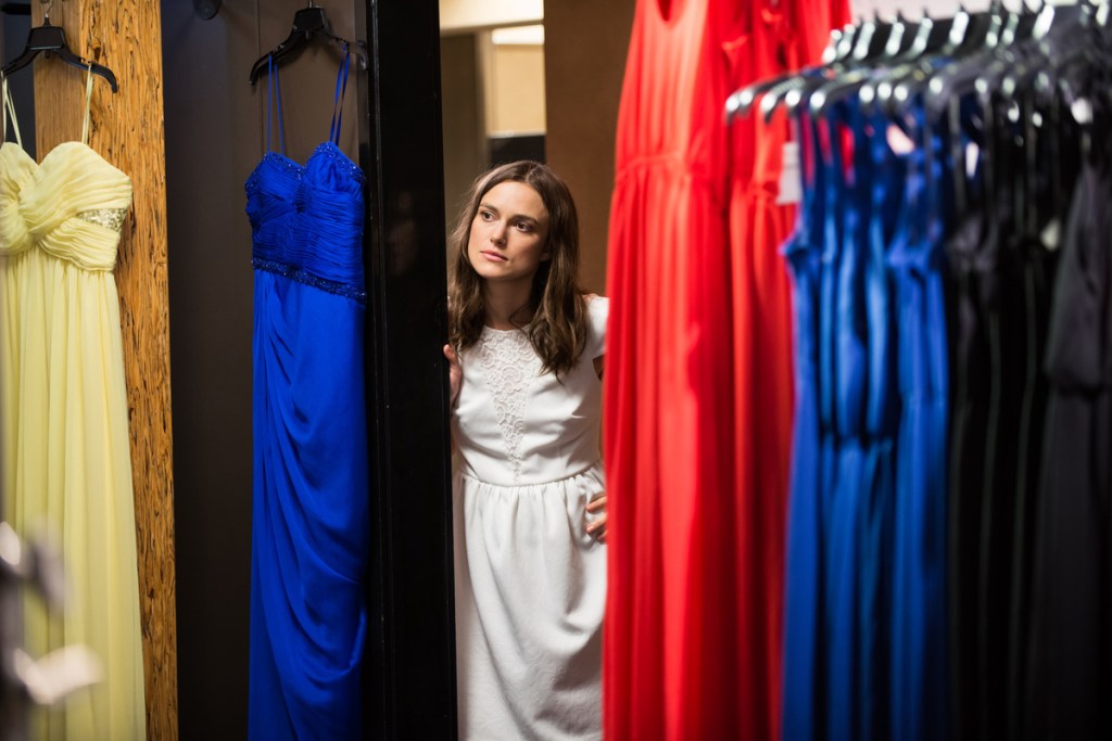 Image from the film Laggies. Megan looks round the corner of a dressing room. She is wearing a white dress.