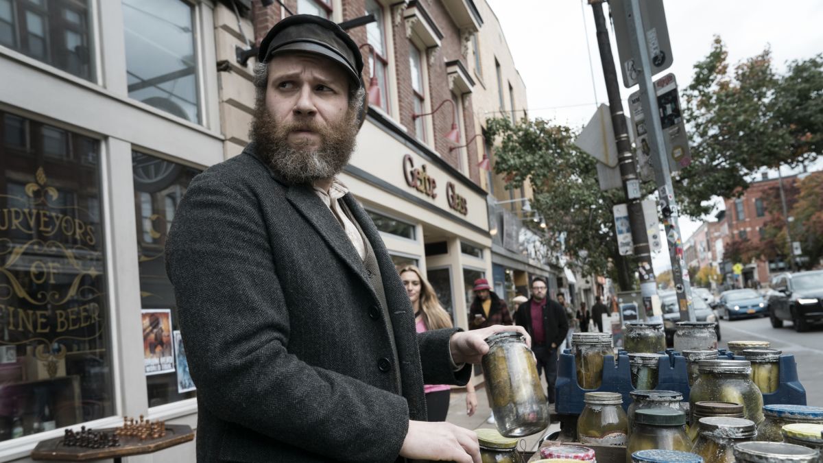 Herschel Greenbaum looks to his right with a concerned expression. He is selling his jars of pickles.