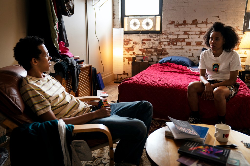 Janay sits opposite Donald in a bedroom. They are in the middle of a discussion.