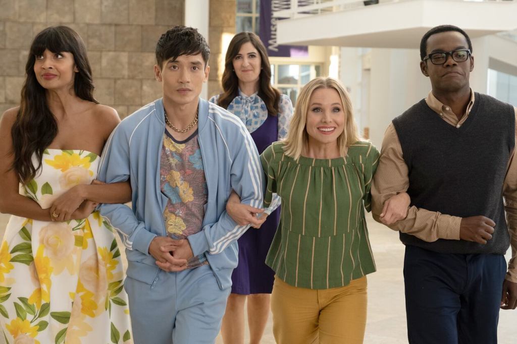 This image is from the TV Show The Good Place. Tahani, Jason, Eleanor and Chidi link arms and walk together. Janet is stood behind them, smiling.