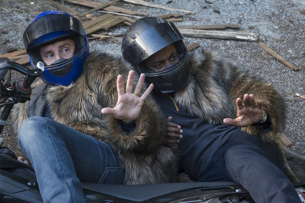 Roday Rodriguez and Hill as Shawn and Gus, lying on the ground dressed in fur coats and motorcycle helmets.