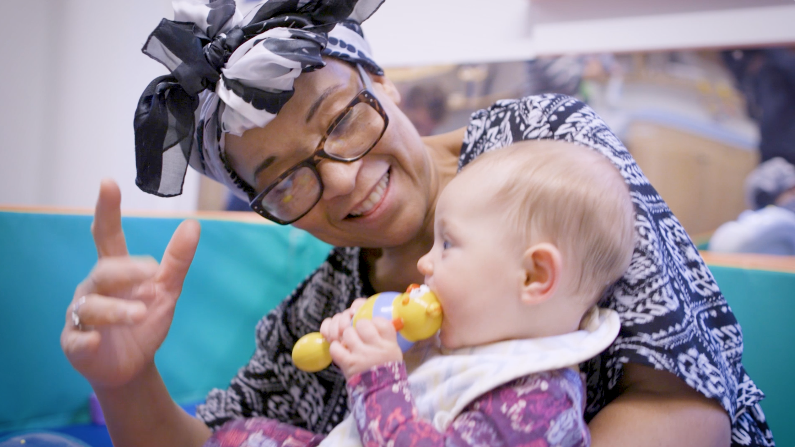A woman holds a baby in her arms and plays with her.