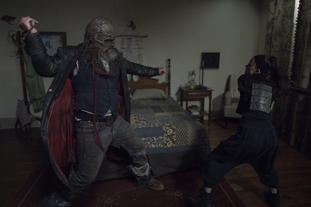 Image still from The Walking Dead episode Stalker. Beta towers over Rosita in a bedroom as they fight to the death.