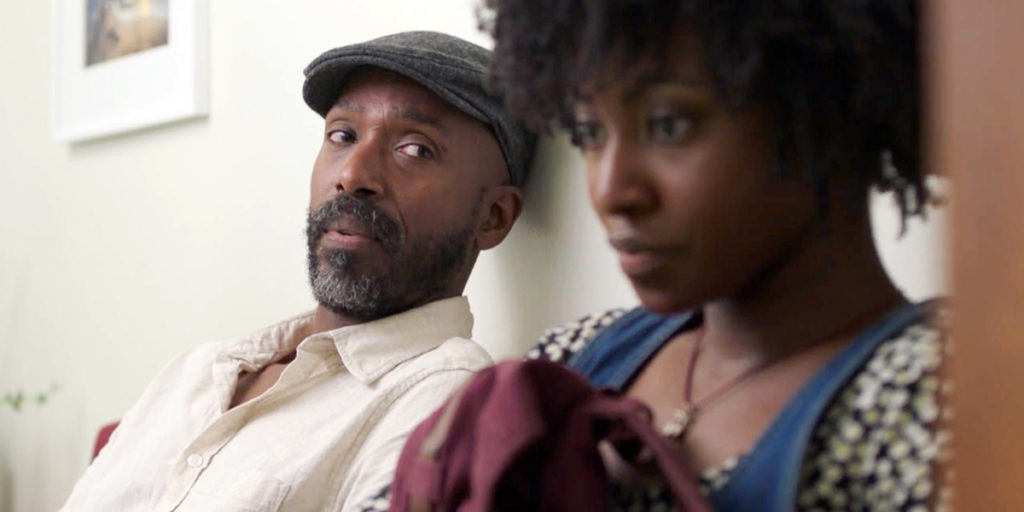Walter and Sylvia sit together in the doctor's waiting room. Walter looks over at his daughter with the gaze of a concerned father.