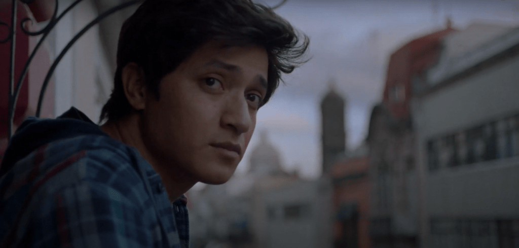 Iván looks out across a balcony, troubled.