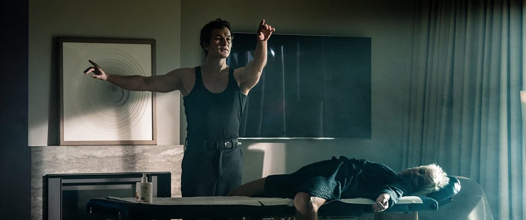 Zhenia lightly dances whilst massaging a woman who lies like she's unconscious.