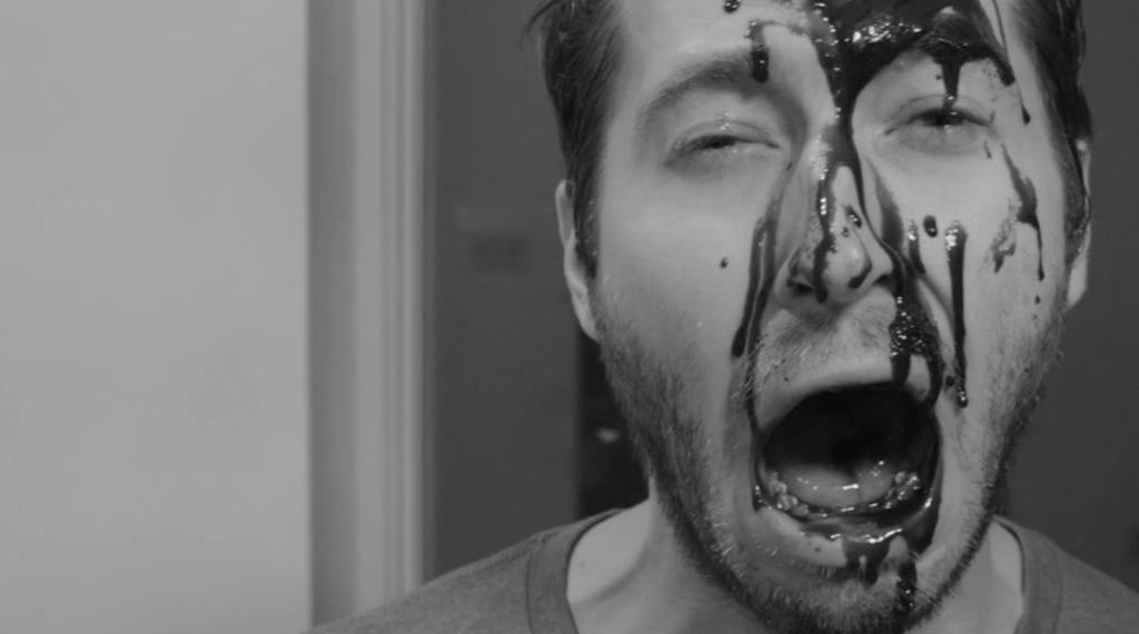 A man screams with blood covering his face. 