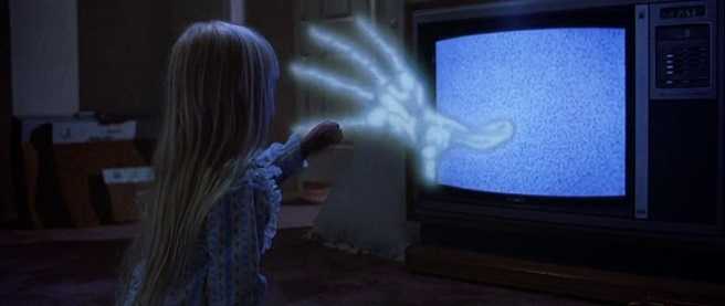 a young girl with blonde hair reaches toward a skeletal hand emerging from glowy static TV