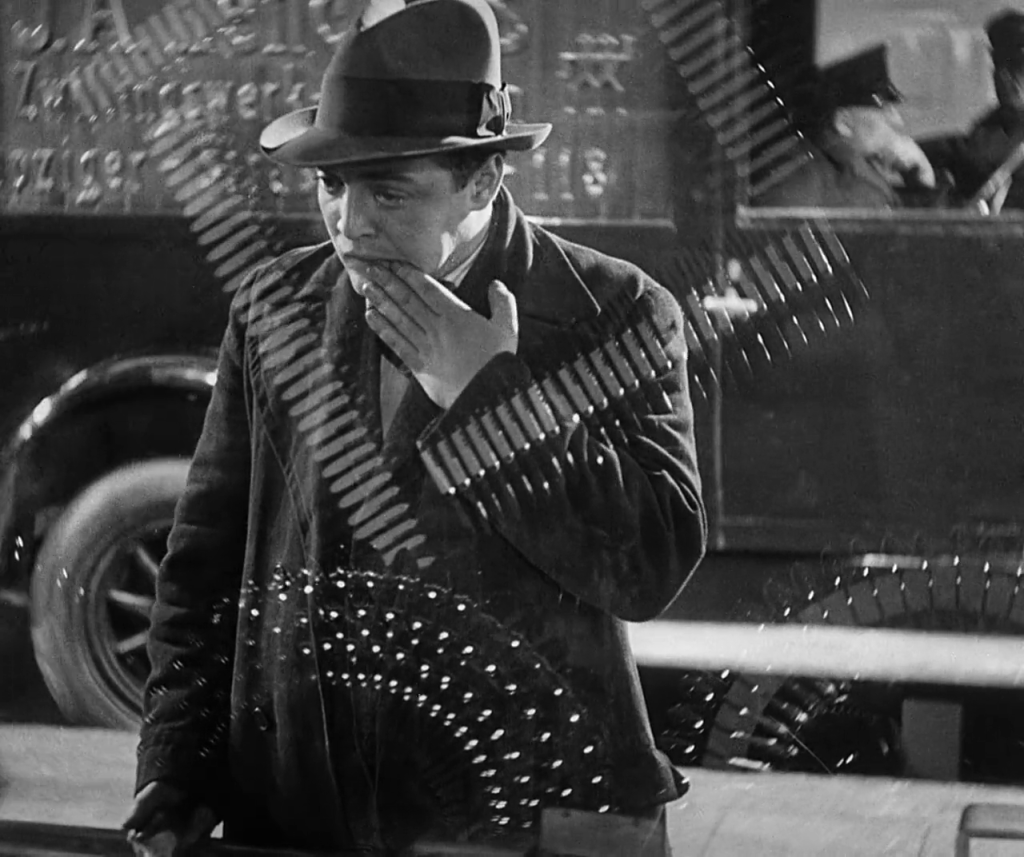 A man looks through a shop window. He wipes something from his mouth.