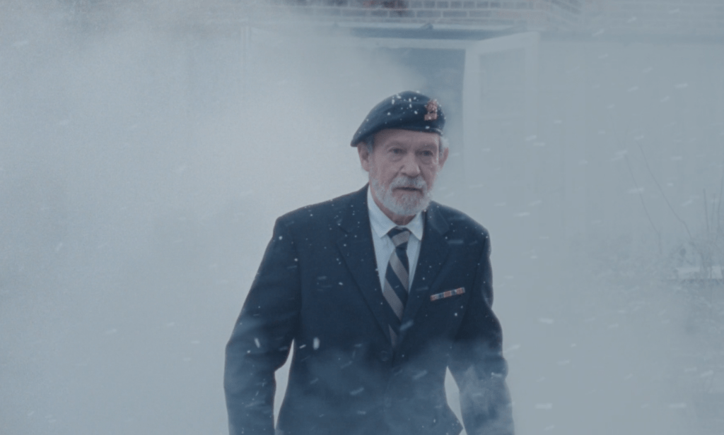 A old military veteran in his uniform tentatively walks towards something amidst white smoke and snow. From 'Thousand Yesterdays'