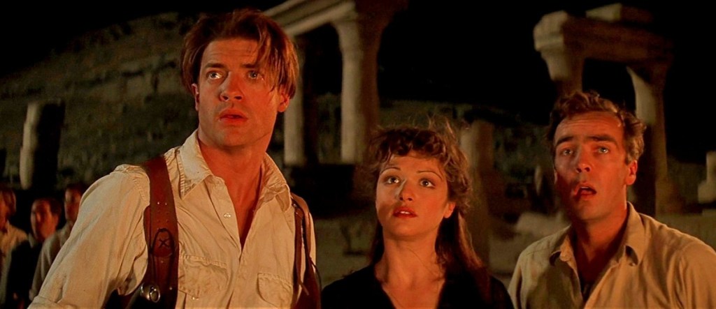 This image is from 'The Mummy' (1999). Rick, Evelyn and Jonathan stand side by side. They're all looking at something in front of them.