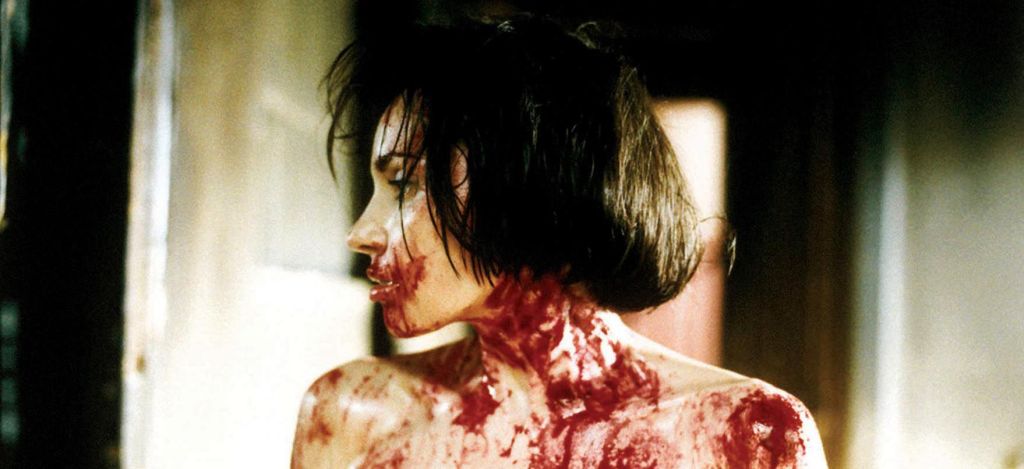 Close up of a white woman with a black bob haircut in profile view. Her mouth, neck, and bare shoulders are smeared with blood.