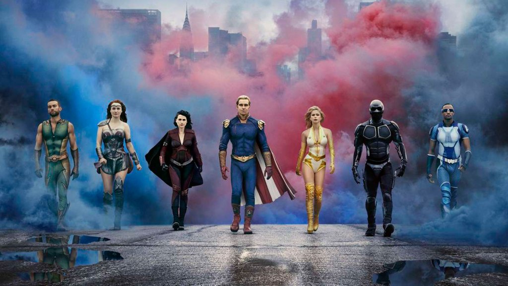 Image from the TV Show 'The Boys'. A group of seven superheroes walk towards the camera. The backdrop behind them is a city covered by red and blue smoke.