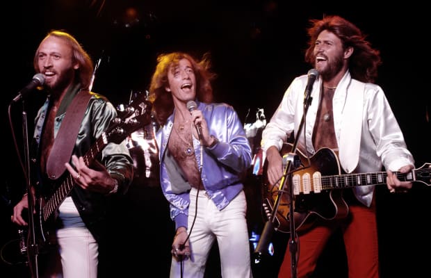 Maurice, Robin, and Barry Gibb singing in concert. 