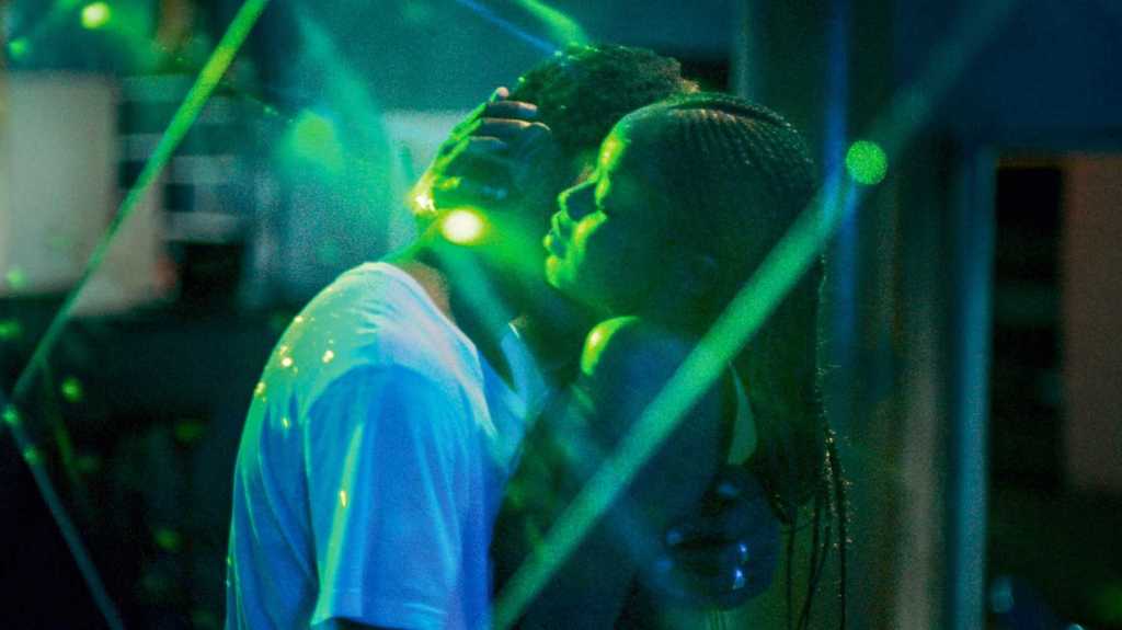 This image is from the film Atlantics. Issa and Ada dance under neon lights at a night club. They are holding one another.