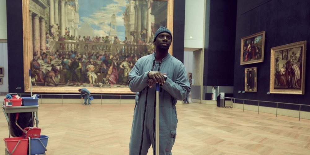 Omar Sy as Assane Diop, dressed as a janitor, surrounded by paintings in the Louvre.