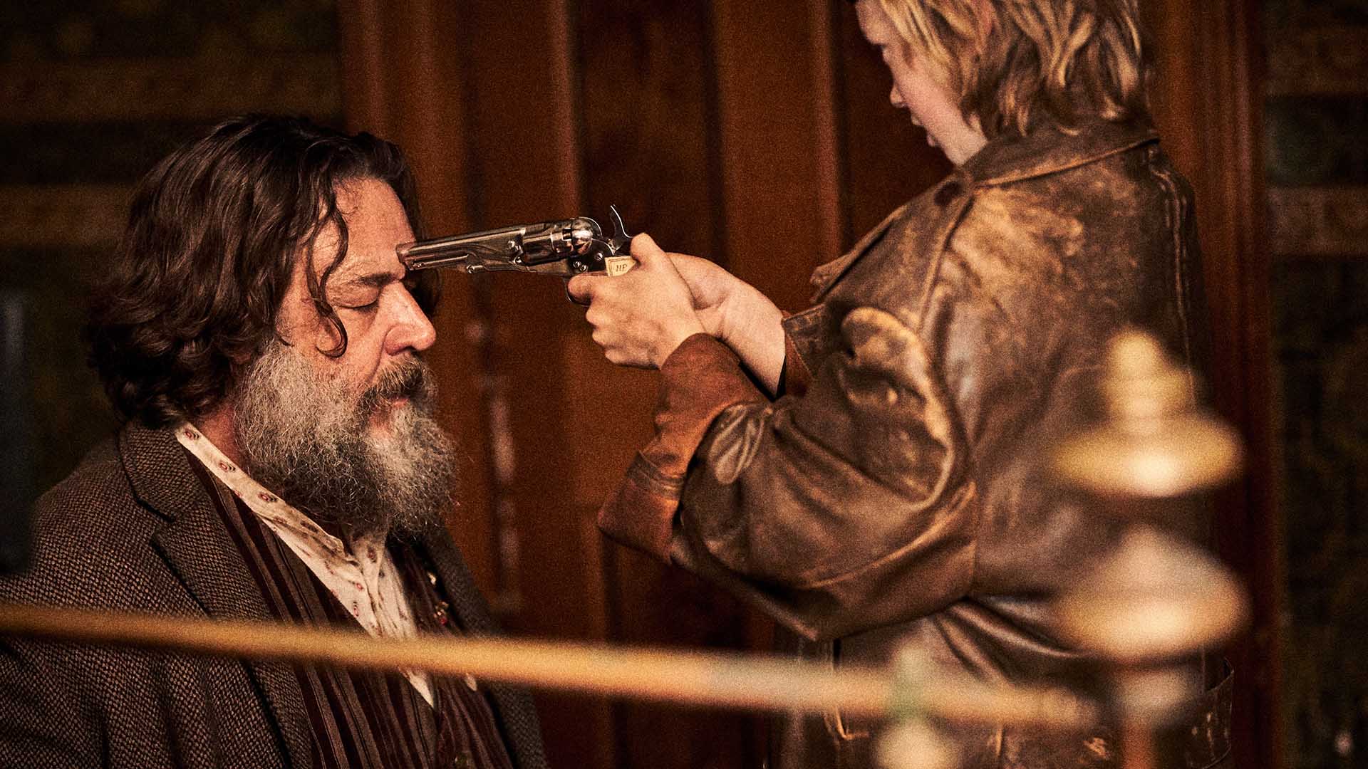 Harry Power (Russell Crowe) at the mercy of a young Ned Kelly (Orlando Schwerdt), who is pointing a gun to his head.