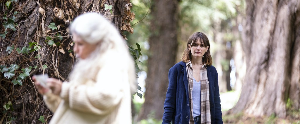 Image from the film 'Relic'. A woman looks with concern at an elderly woman who is reading something in front of a tree.