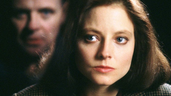 Image is from the film 'The Silence of the Lambs' (1991). Clarice looks seriously and earnestly at the devilish face of Hannibal, reflected imposingly for the audience in the glass