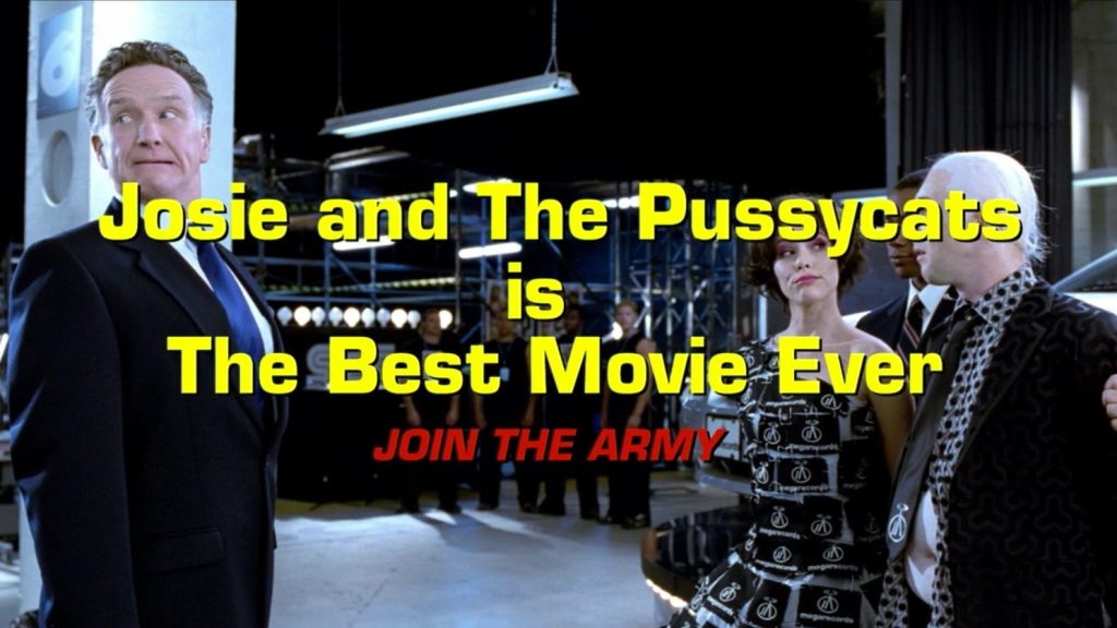 Large yellow and red text that reads "Josie and the Pussycats is The Best Movie Ever JOIN THE ARMY" is set over an image of Parker Posey and Alan Cumming standing across from a white man in a suit