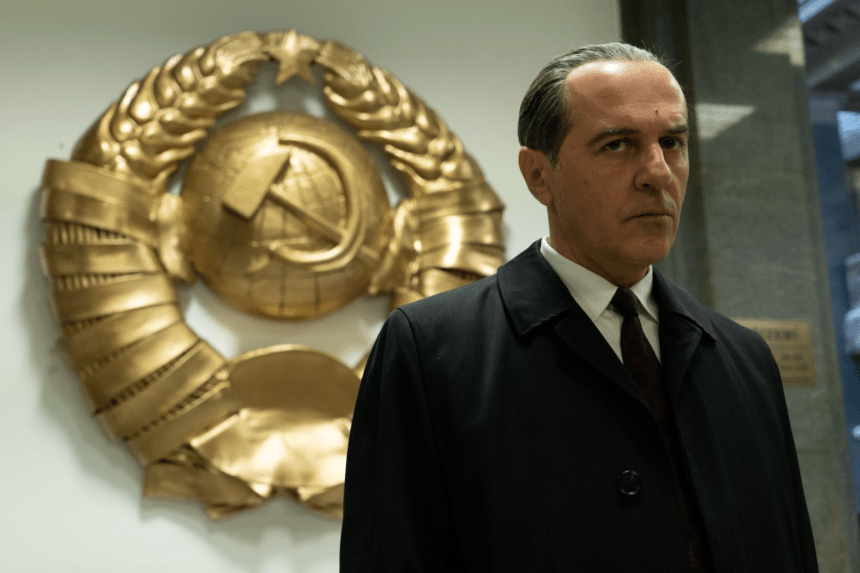 Merab Ninidze standing in front of a hammer and sickle; symbol of the USSR.