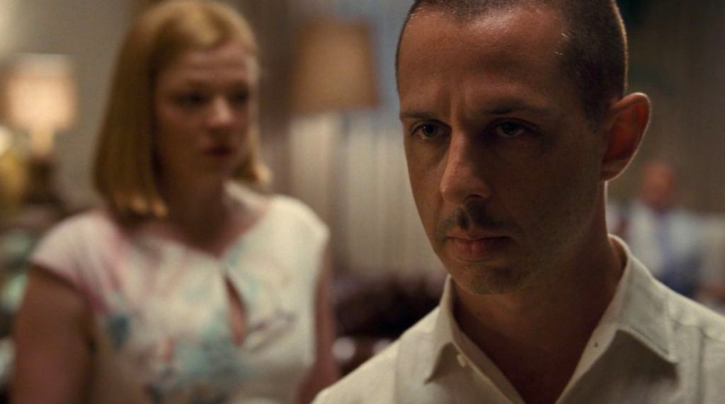 Close-up shot of Jeremy Strong as Kendall Roy. Sarah Snook as Shiv Roy is standing behind him, but her figure is out of focus. 