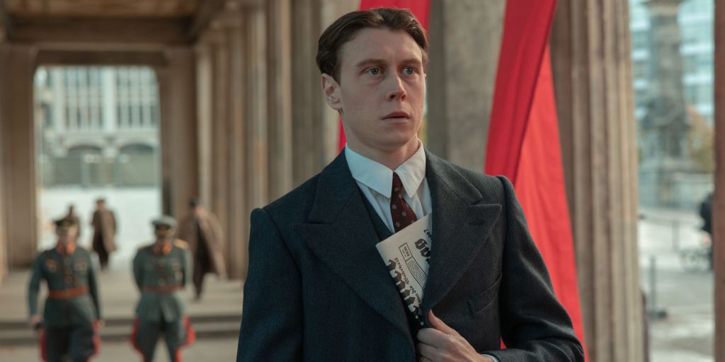 Legat (George MacKay) looks anxious, suited but with a newspaper hidden by jacket