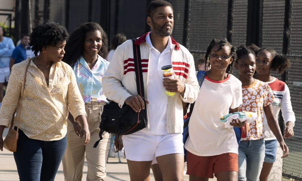 A still of Will Smith and the rest of the main cast of 'King Richard' walking down the street. They wear casual and sporty clothes, and appear determined.