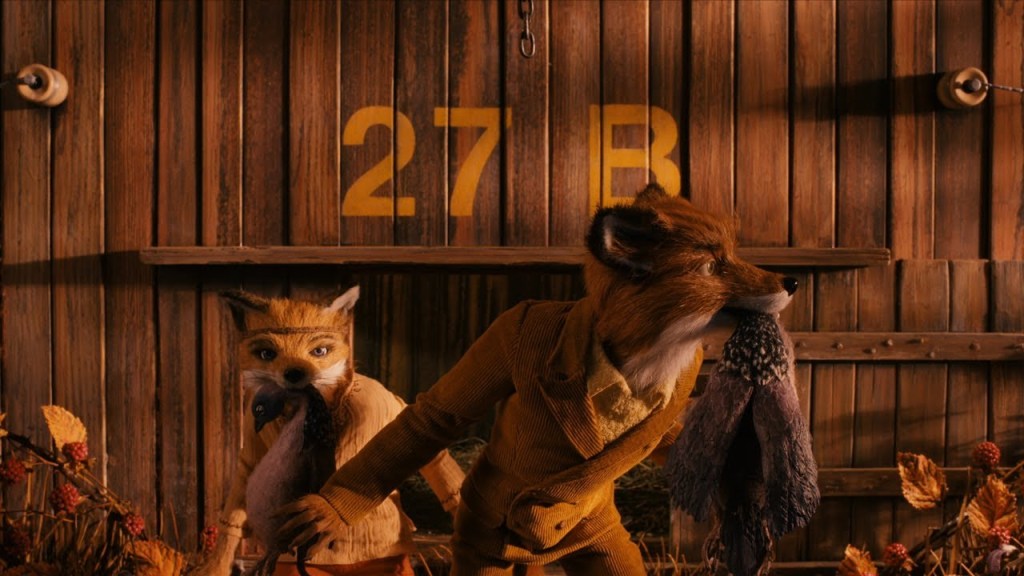Mr Fox (George Clooney) and son Ash (Jason Schwartzman), from Fantastic Mr. Fox, looking around themselves as they each have a dead animal in their mouths. The frame is filled with warm autumnal hues, with burnt reds, oranges, yellows, and browns dominating.