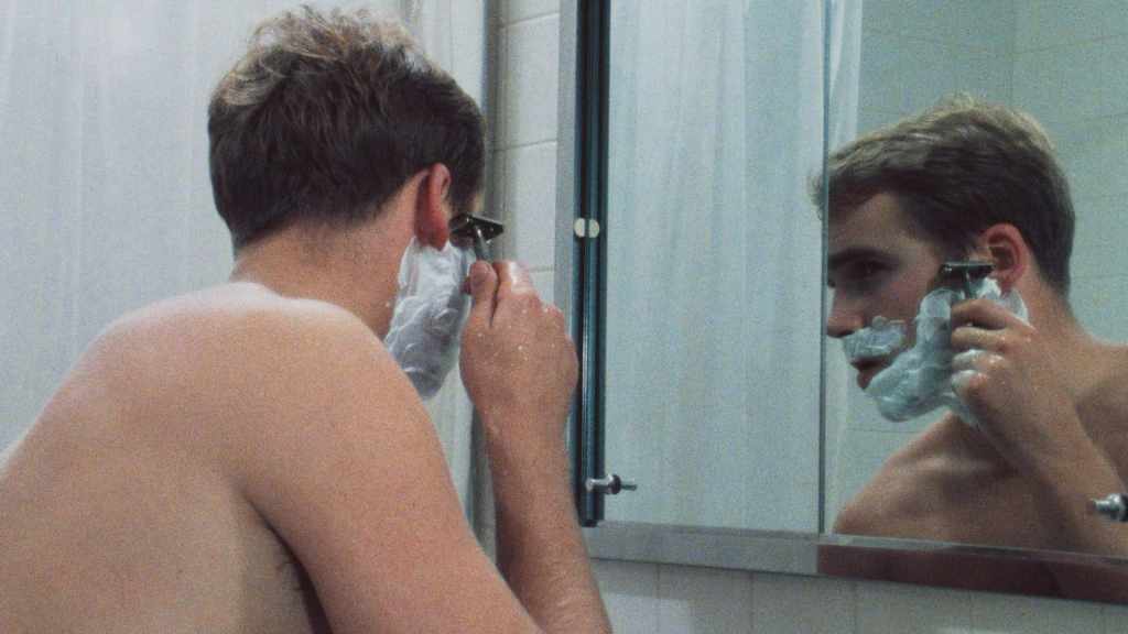 A still from The Big Shave showing the male protagonist looking at himself in the mirror while about to being his first shave. 