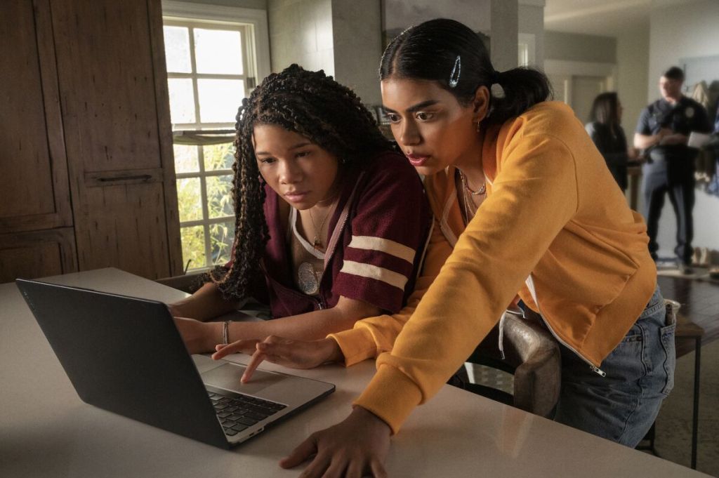 protagonist and friend look intrigued and nervous looking at a laptop. 