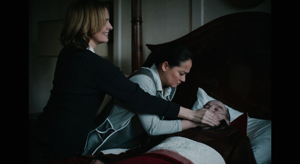 A still from 'Raging Grace' of Katherine (Leanne Best) and Joy (Maxene Eigenmann), who are clamping a hand over a bedridden Mr Garrett's (David Hayman) mouth.