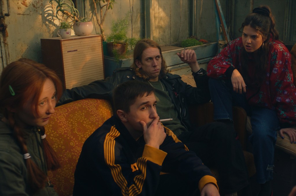 Tonia's new friends pictured, including Lera and her brother Sania. Sania is smoking a cigarette and looking at Tonia outside of the frame. Judging by Lera's facial expression, they are talking about something intensely. 