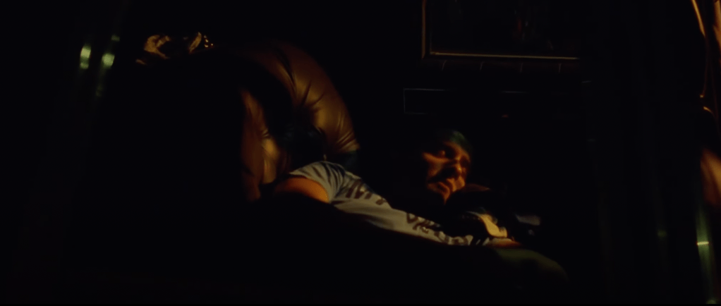 Dark still of Alejandro lying down sleeping, there is only little light shining through, showing the contours of his face but the setting in which he is in is not detailed.